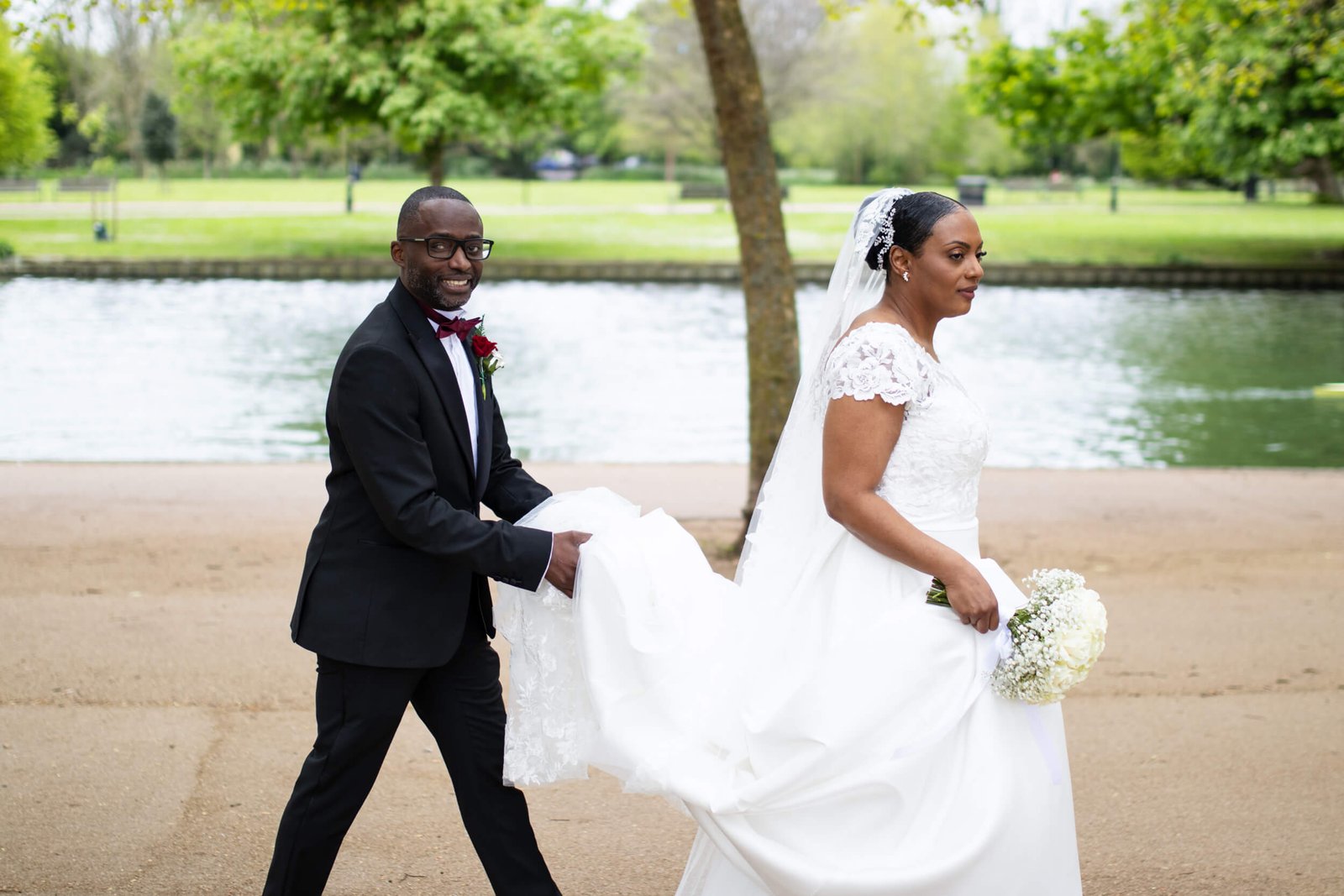 Bride and groom walking together beside a lake